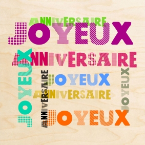 Des joyeux anniversaire imprimés en couleur sur une belle carte en bois.